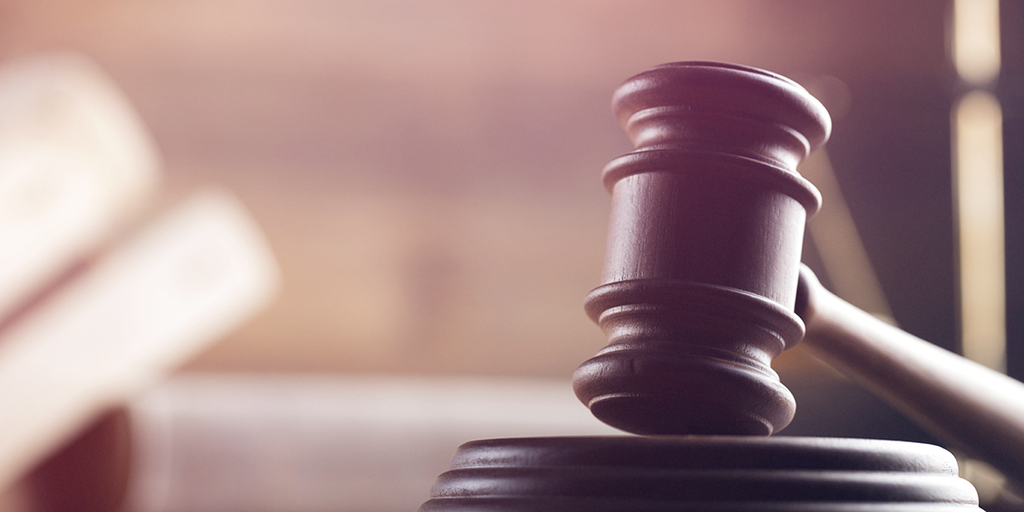 An image of a judge's gavel on a desk with a light color overlay