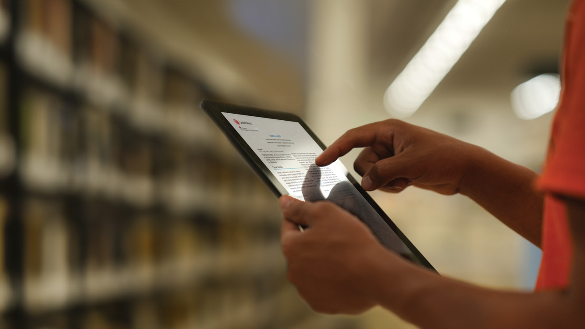 Focused view of a person holding a tablet, featuring the LexisNexis Inmate Law Library interface.