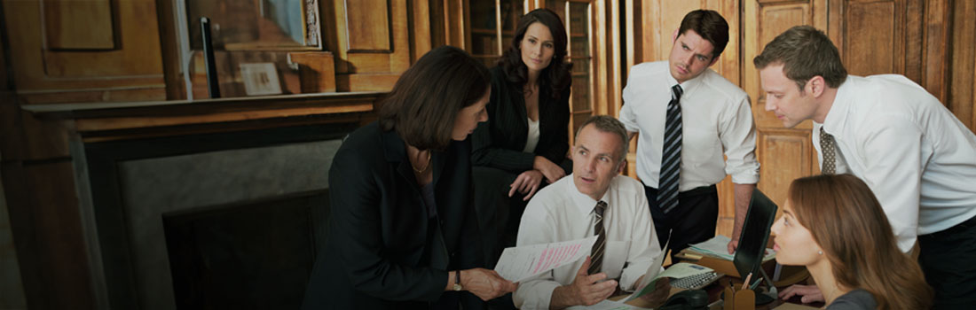 lawyers sitting at boardroom table in a corporate legal department reviewing enterprise legal management features for software